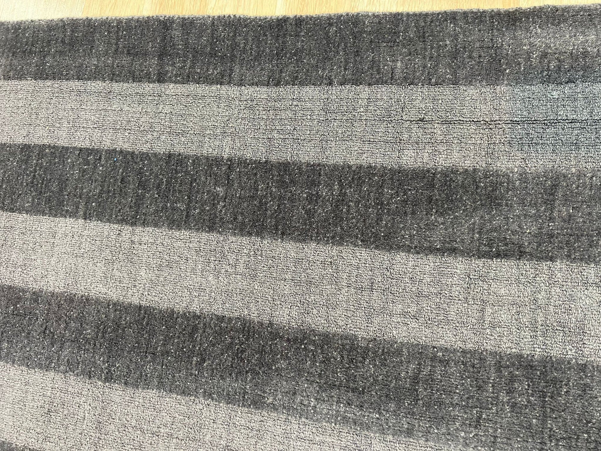 Yara Alluring Gray Handmade Wool Rug, its soft gray tones and subtly textured weave complementing a light wood floor and minimalist interior.