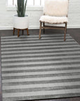 Yara Alluring Gray Handmade Wool Rug displayed in a brightly lit living room. Neutral furniture complements the rug's subtle gray tones and hand-woven wool construction, creating a sophisticated and inviting atmosphere.