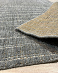 Delicate Giselle Gray Handmade Wool Rug, displaying subtle gray variations and intricate detailing, resting on a light wood floor in a bright, modern interior.