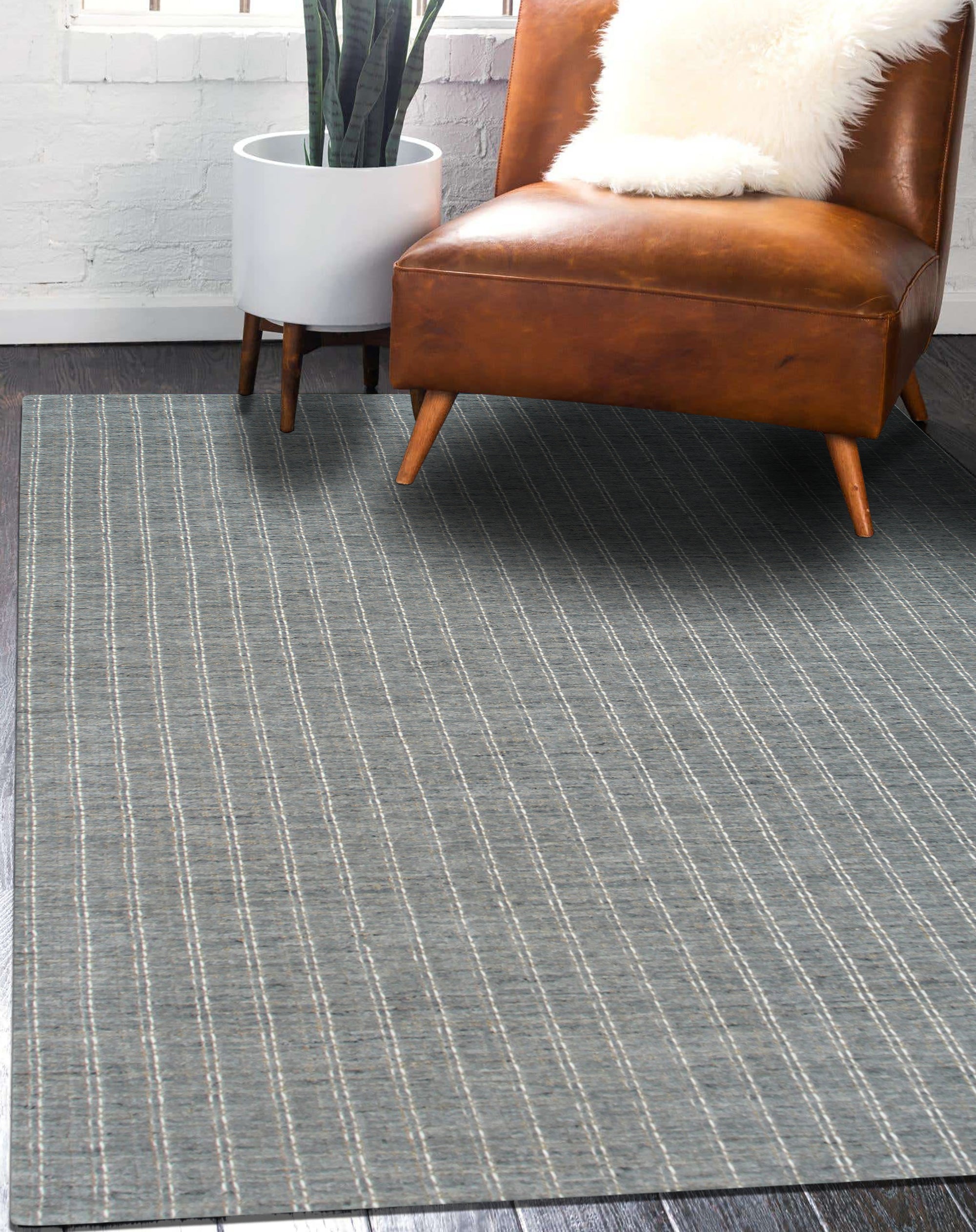 Delicate Giselle Gray Handmade Wool Rug, its subtle gray tones and delicate design complementing a modern living space with a gray couch and patterned pillows.