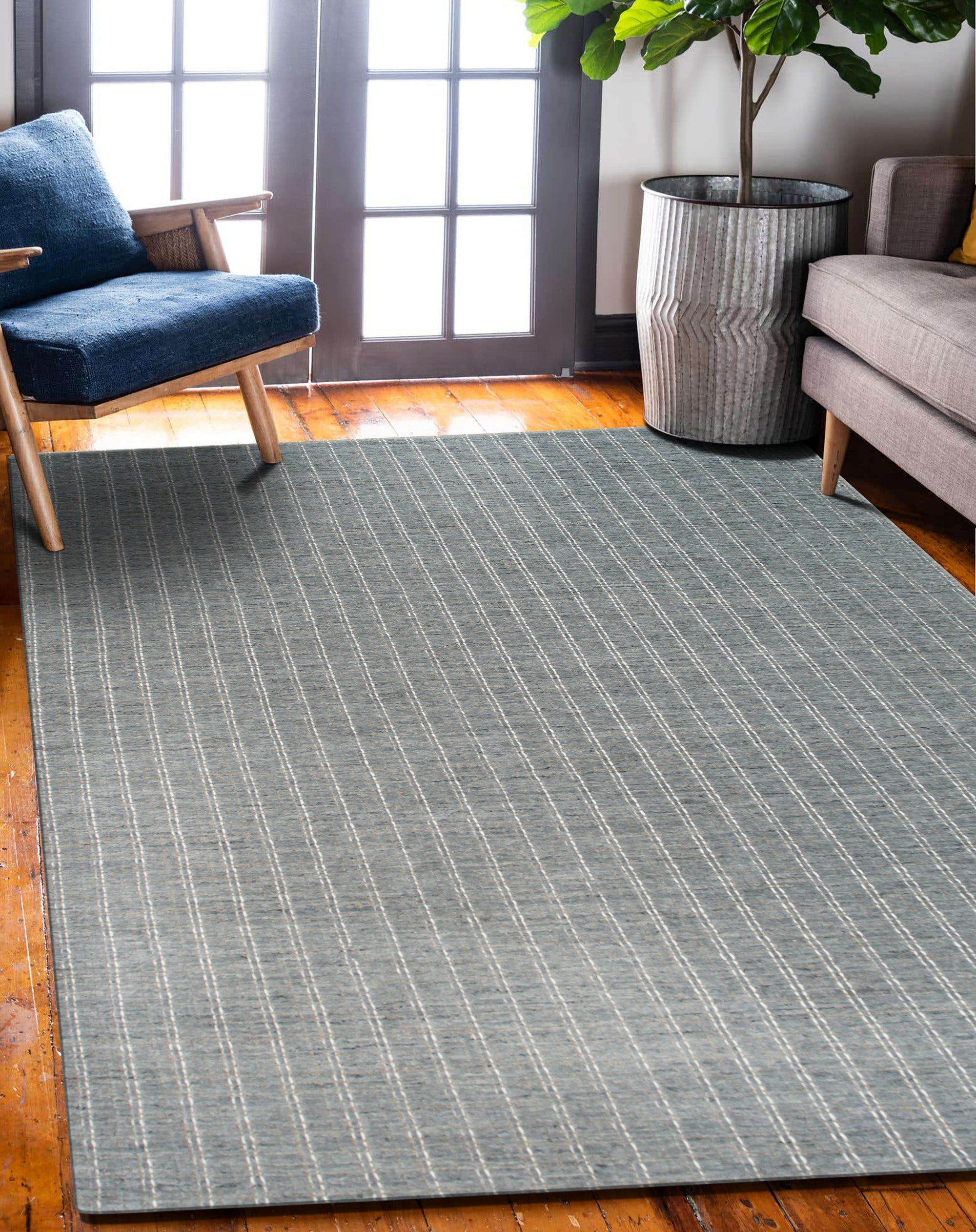Delicate Giselle Gray Handmade Wool Rug, seen partially rolled and angled upwards, reveals its woven texture and subtle gray color variations across the wool fibers.