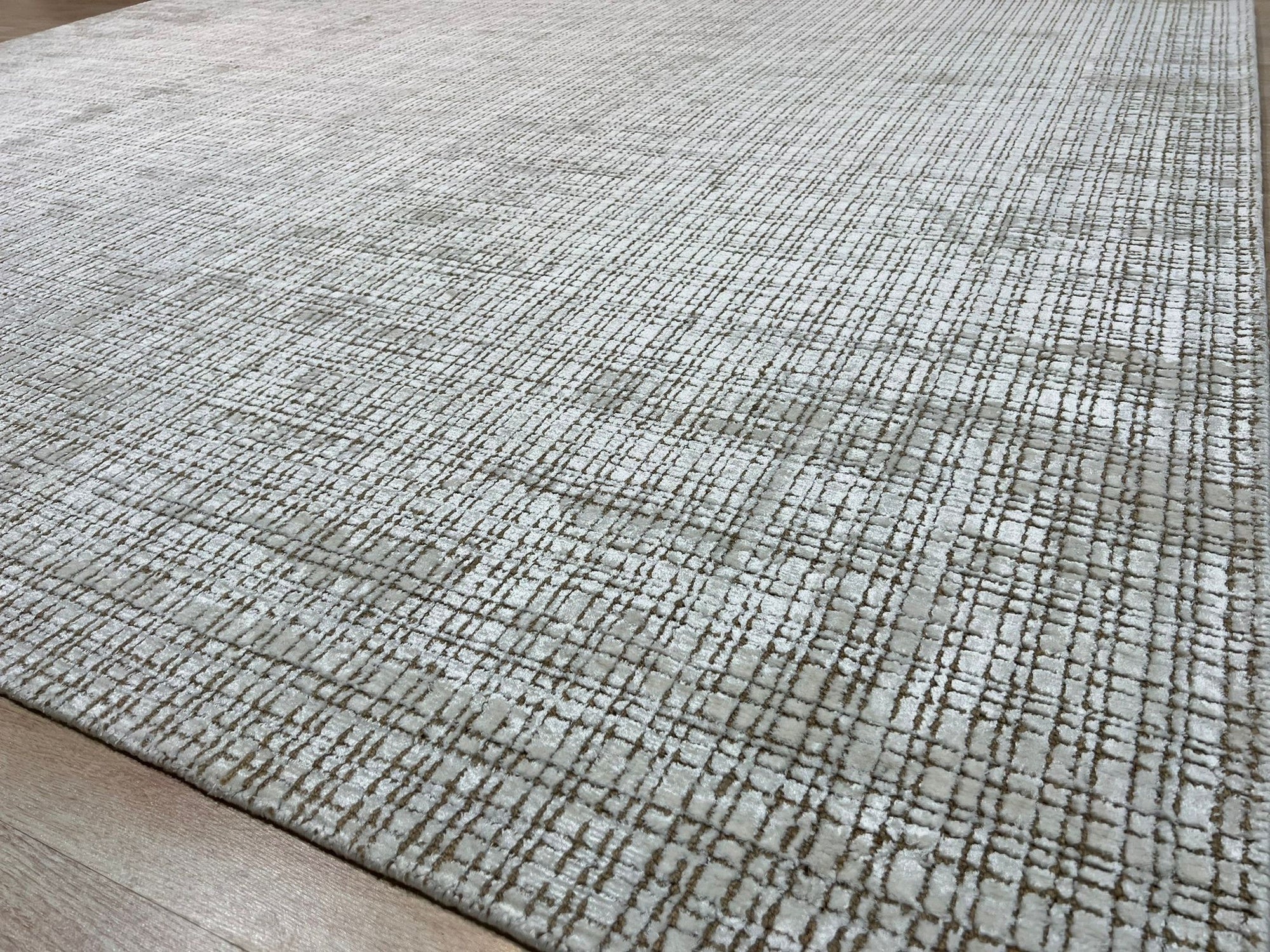 Warm Sarrah White Handmade Bamboo Silk Rug, subtly textured ivory expanse radiating soft sheen, hand-knotted bamboo silk creating depth, observed within a room setting featuring contemporary furniture.