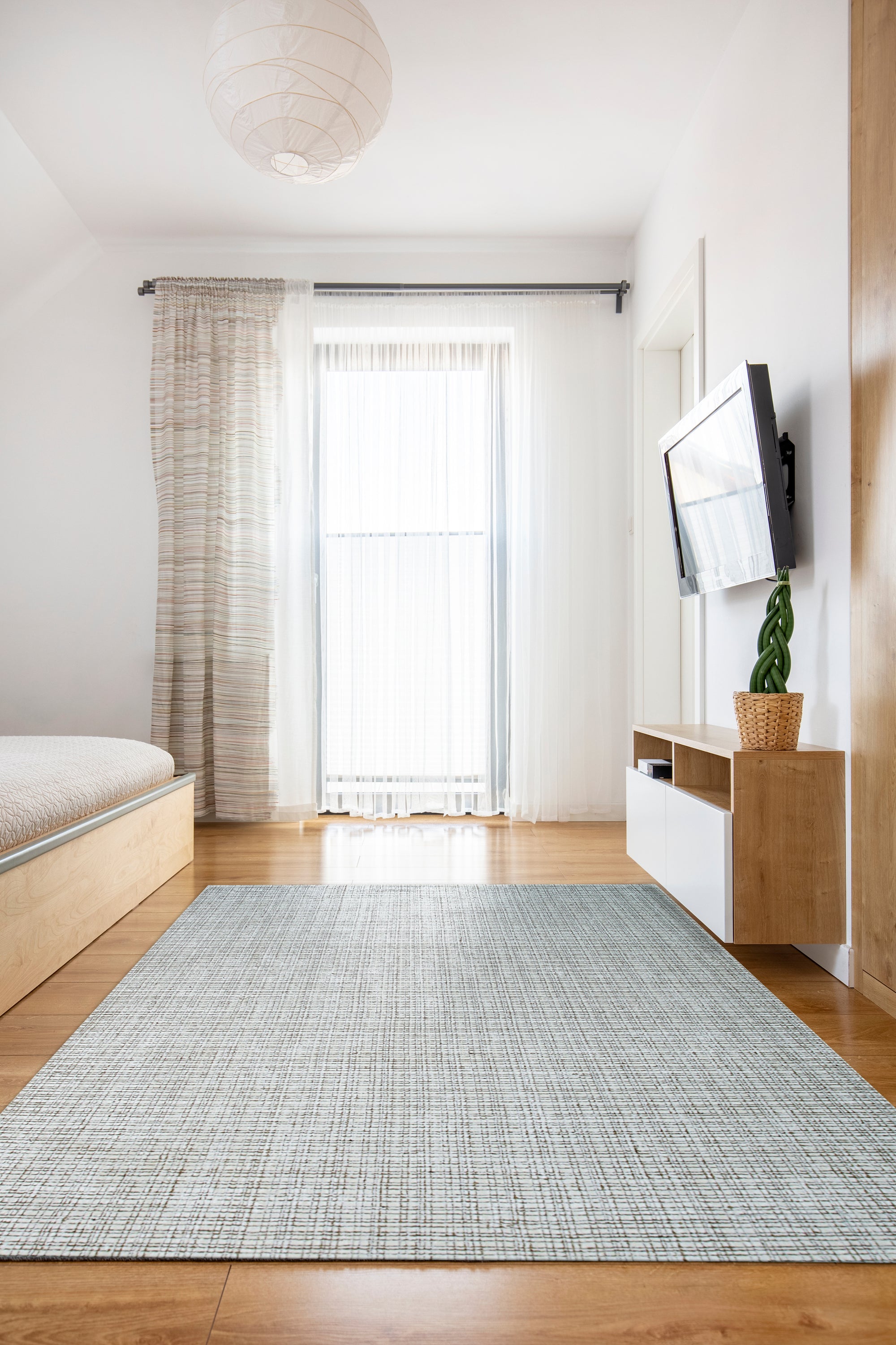 Warm Sarrah White Handmade Bamboo Silk Rug graces a minimalist living space, its subtle sheen catching the light; a calming oasis of cream tones lending sophisticated texture to the contemporary interior.