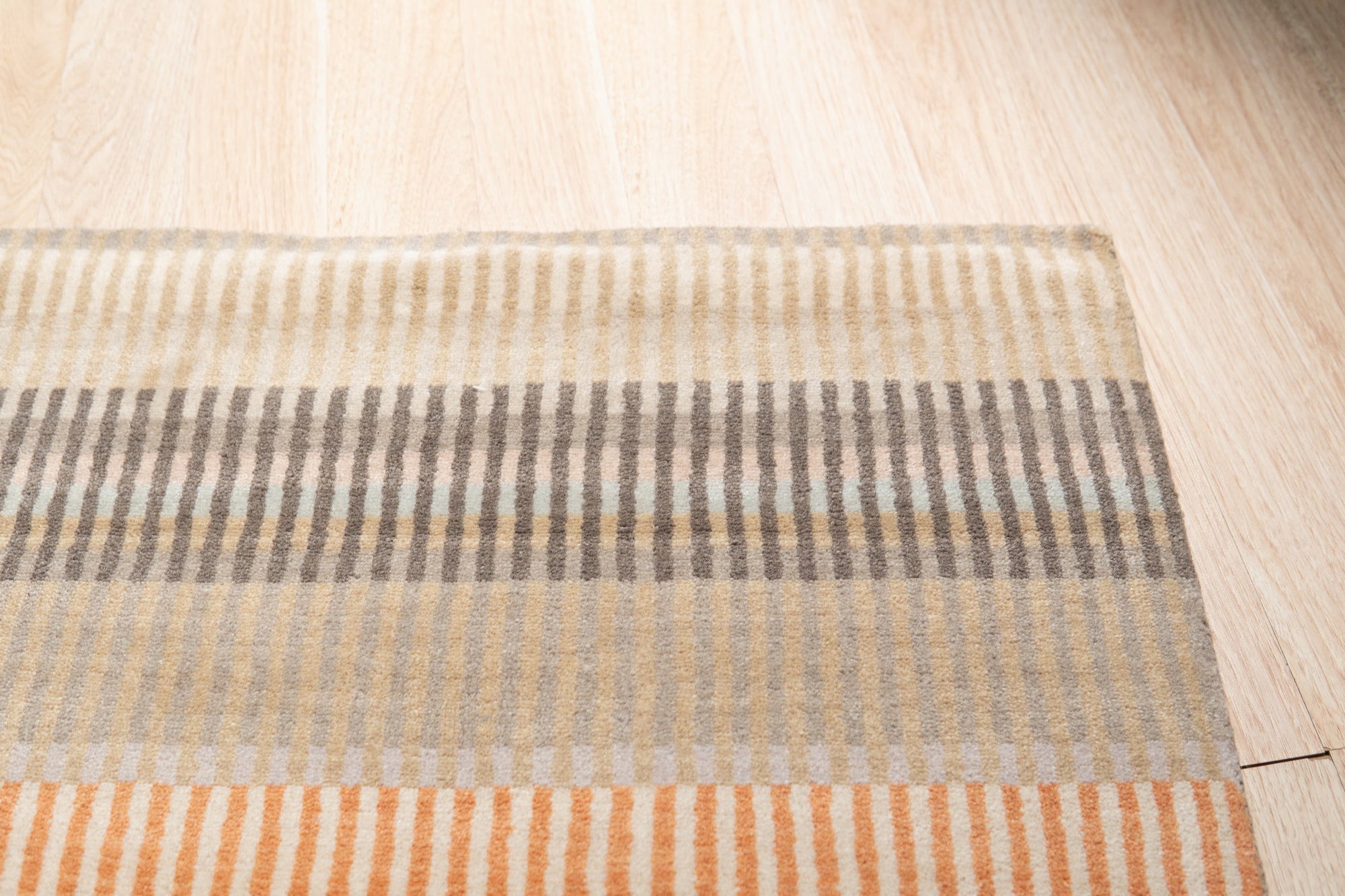 Louie Ophelia Beige Handmade Wool Rug, displaying intricate patterns and textures in soft beige tones, covers the floor in a well-lit living space.