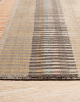 Louie Ophelia Beige Handmade Wool Rug, exhibiting a subtle, elegant pattern in soft beige tones, lays flat against a light floor, showcasing its texture and overall design within a room setting.