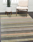 Louie Ophelia Beige Handmade Wool Rug, displaying intricate patterns and a soft beige hue, complements a modern living space with dark wood flooring and a minimalist aesthetic.