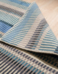 Louie Ophelia Ocean Blue Handmade Wool Rug, presenting a swirling, watery design in shades of blue, cream, and hints of brown, laid flat showcasing its intricate hand-knotted construction.