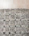 Nadia Ava Gray Handmade Wool Rug, soft gray wool rug with subtle pattern variations, displayed in a bright, minimalist living room setting with light wood floors and modern furniture.