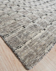 Nadia Ava Gray Handmade Wool Rug in a warmly lit living room, blending seamlessly with neutral furniture and hardwood floors. Gray tones in the rug create subtle patterns, providing a grounding element in the modern interior.