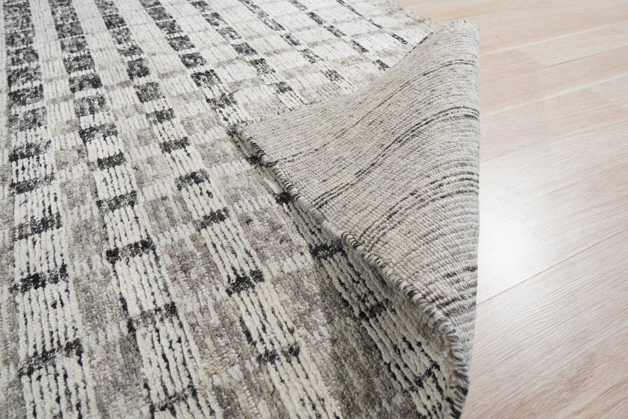 Nadia Ava Gray Handmade Wool Rug, featuring a subtle geometric pattern in varying shades of gray, displayed in a living room setting with modern furniture.