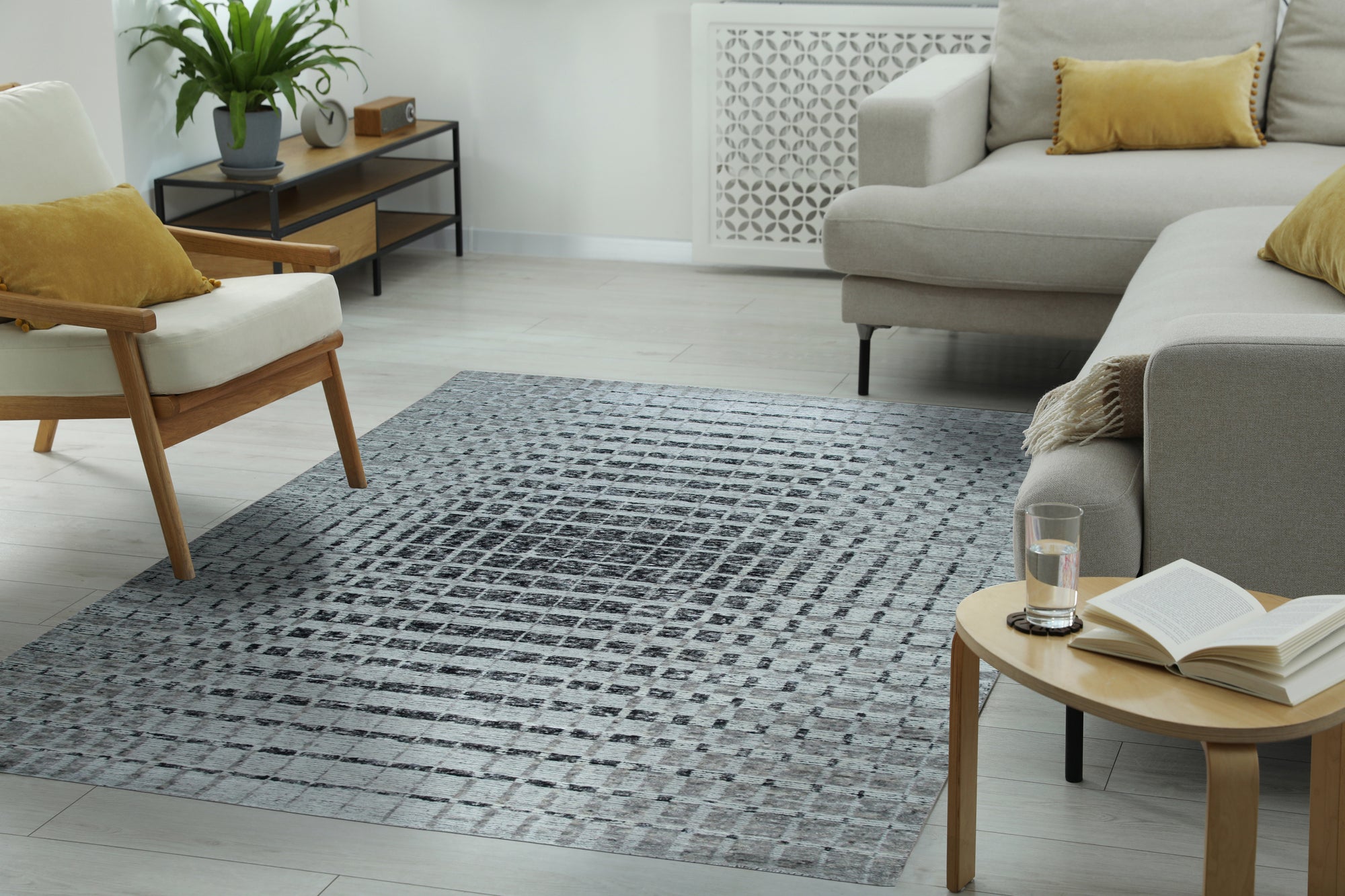 Nadia Ava Gray Handmade Wool Rug, softening a bright, modern living room. Neutral hues and subtle texture of the wool rug ground a space with white walls, a minimalist sofa, and natural light pouring through a window.