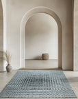 Nadia Ava Gray Handmade Wool Rug, blending subtle gray tones in a woven wool texture, partially visible beneath a light wood coffee table and modern cream-colored sofa.