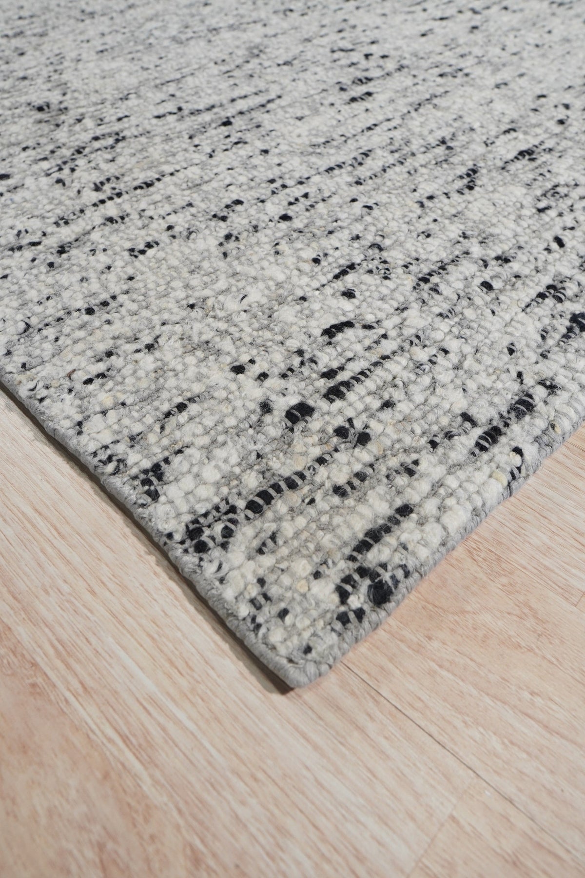 Opulent Alluring Dark Gray Handmade Wool Rug, a dark gray wool rug with subtle textural variations, lies softly on a hardwood floor, its rich color grounding the minimalist space.