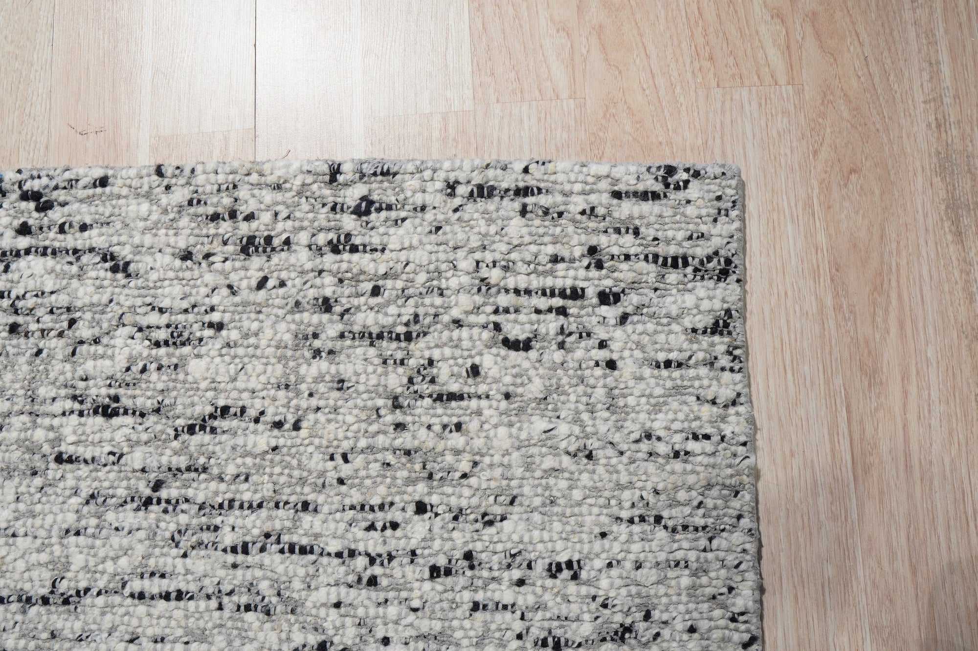 Opulent Alluring Dark Gray Handmade Wool Rug gracing a modern living space, its deep charcoal tones grounding light wood flooring and complementing a minimalist aesthetic. Hand-knotted wool provides a plush, inviting texture.
