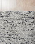 Opulent Alluring Dark Gray Handmade Wool Rug gracing a modern living space, its deep charcoal tones grounding light wood flooring and complementing a minimalist aesthetic. Hand-knotted wool provides a plush, inviting texture.