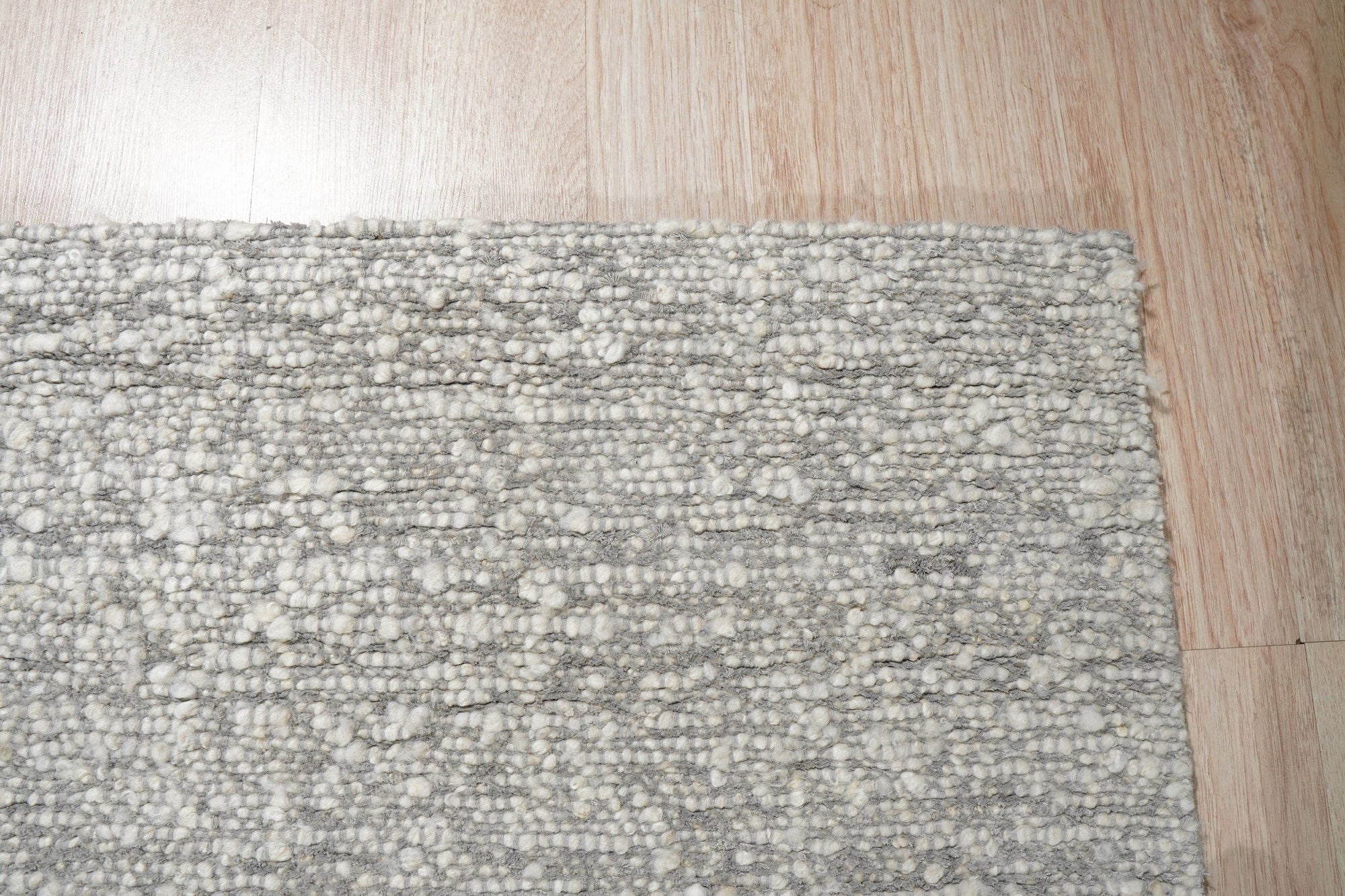 Opulent Alluring Silver Handmade Wool Rug, soft silver tones shimmer in this luxurious wool rug, showcasing intricate hand-knotted construction with subtle textural variations, nestled within a modern living space.
