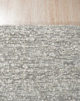 Opulent Alluring Silver Handmade Wool Rug, soft silver tones shimmer in this luxurious wool rug, showcasing intricate hand-knotted construction with subtle textural variations, nestled within a modern living space.