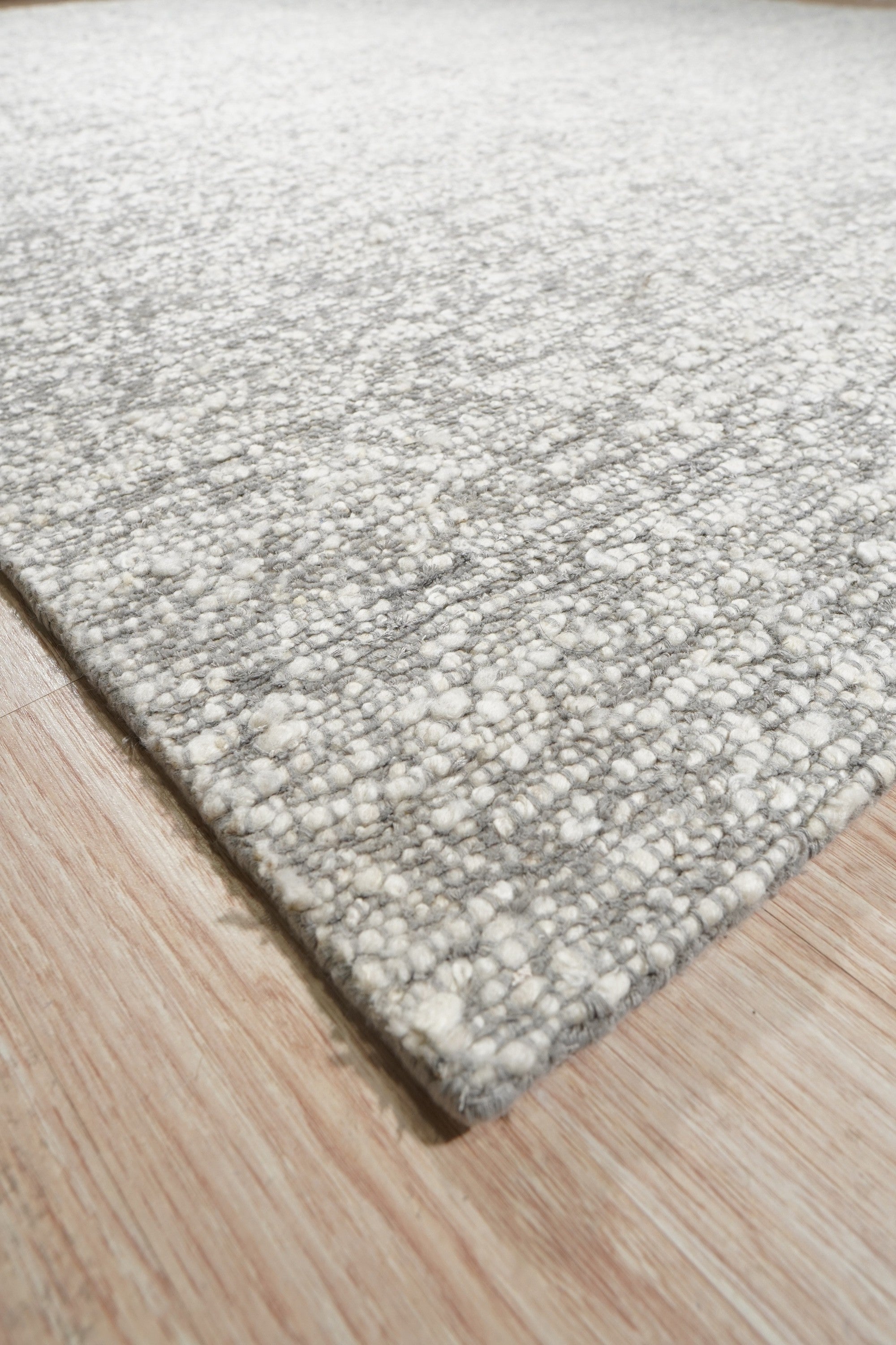 Opulent Alluring Silver Handmade Wool Rug, its shimmering silver tones and dense wool pile creating a luxurious and inviting texture on a light-toned floor.