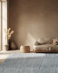 Tessa Maya Gray Hand Knotted Wool Rug, its intricate geometric pattern and subtle gray tones lending sophisticated texture to a warmly lit, modern living room setting.