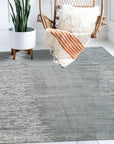 Tessa Maya Gray Hand Knotted Wool Rug, showcasing a textured geometric pattern in varying shades of gray, lays elegantly on a light hardwood floor, inviting warmth and subtle sophistication into the space.