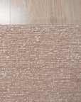 Freya Graceful Pink Handmade Wool Rug, showcasing its soft pink hues and plush wool texture, rests elegantly on a light hardwood floor, its subtle pattern adding warmth and a touch of handcrafted luxury to the room.