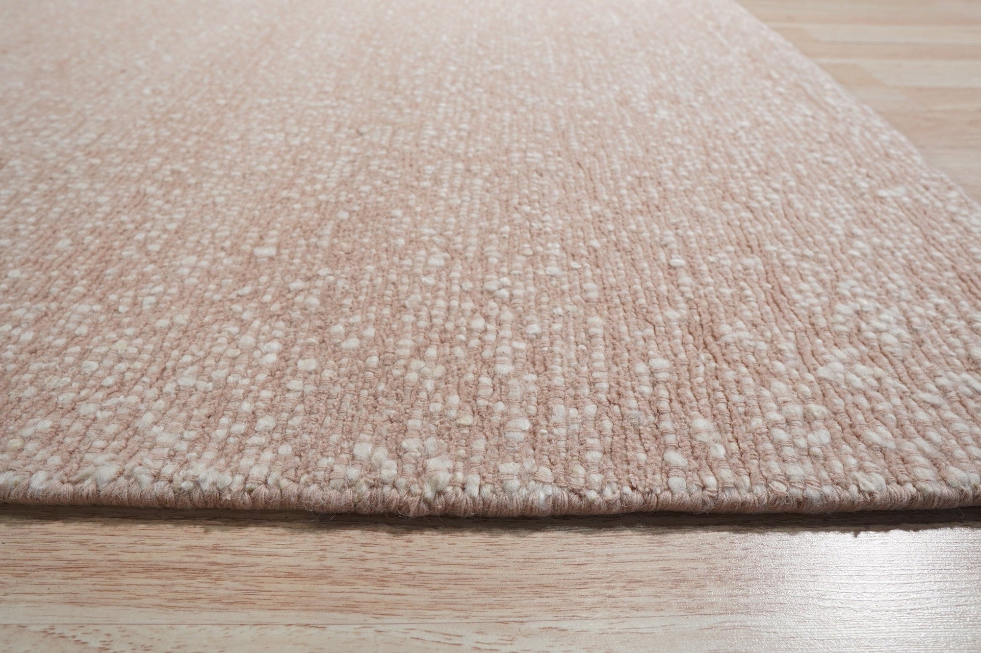 Freya Graceful Pink Handmade Wool Rug, softly lit detail highlighting its texture and the subtle variations in pink wool.