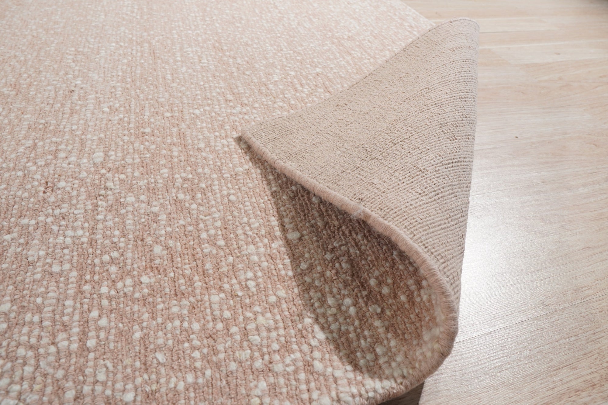 Freya Graceful Pink Handmade Wool Rug, a soft pink wool rug with subtle variations in color and texture, seen in a well-lit room, highlighting its plush pile and hand-knotted construction.