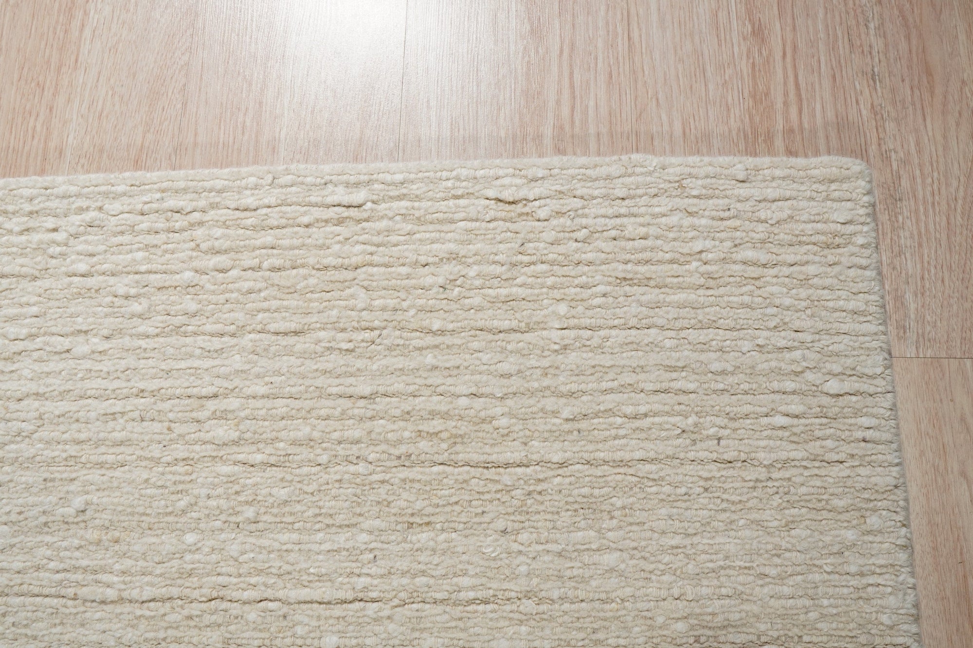 Bespoke Delicate Ivory Handmade Wool Rug, softly textured wool pile in warm ivory, inviting touch and subtle visual depth on a light hardwood floor.