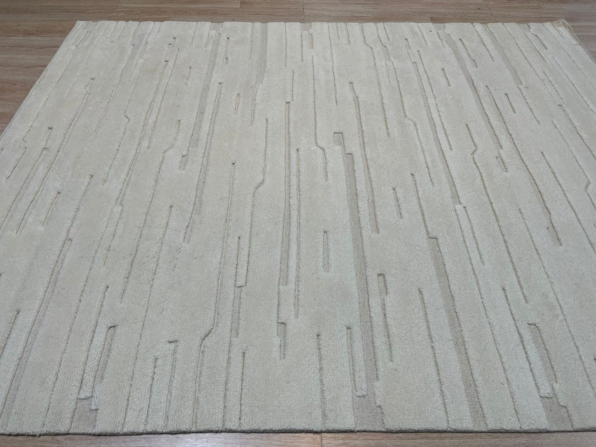Para Vibrant White Hand Knotted Wool Rug, luminous hand-knotted wool shimmers in a minimalist living room setting. Neutral furnishings complement the rug’s texture and subtle design.