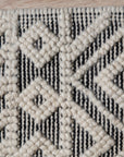Maya Diamond Black Handmade Wool Rug, its geometric diamond pattern rendered in contrasting shades, lending a modern, textured look to a well-lit interior.