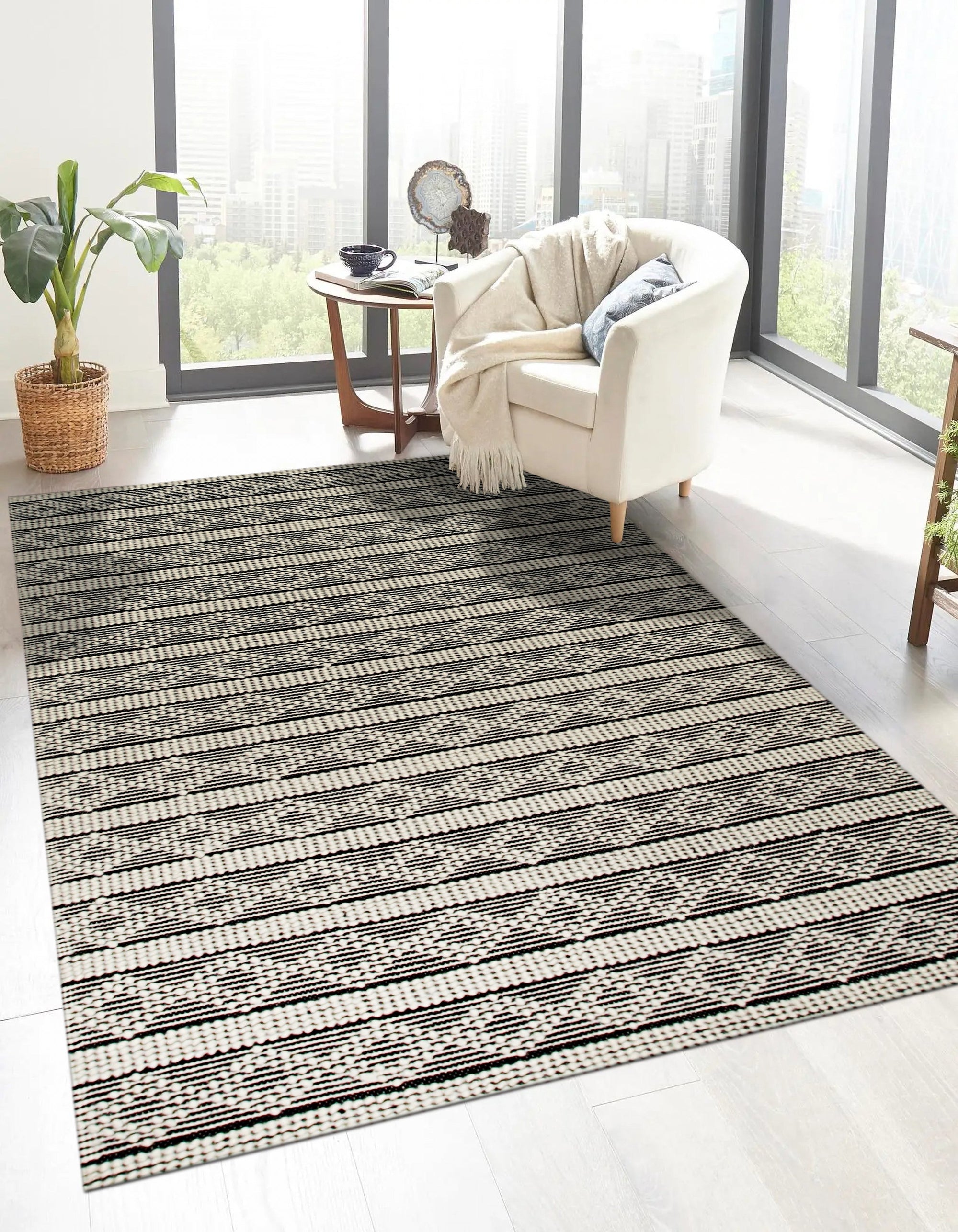 Selene Striped Black Handmade Wool Rug, contrasting bands of black and off-white wool define this textured rug, laid in a minimalist living room setting.