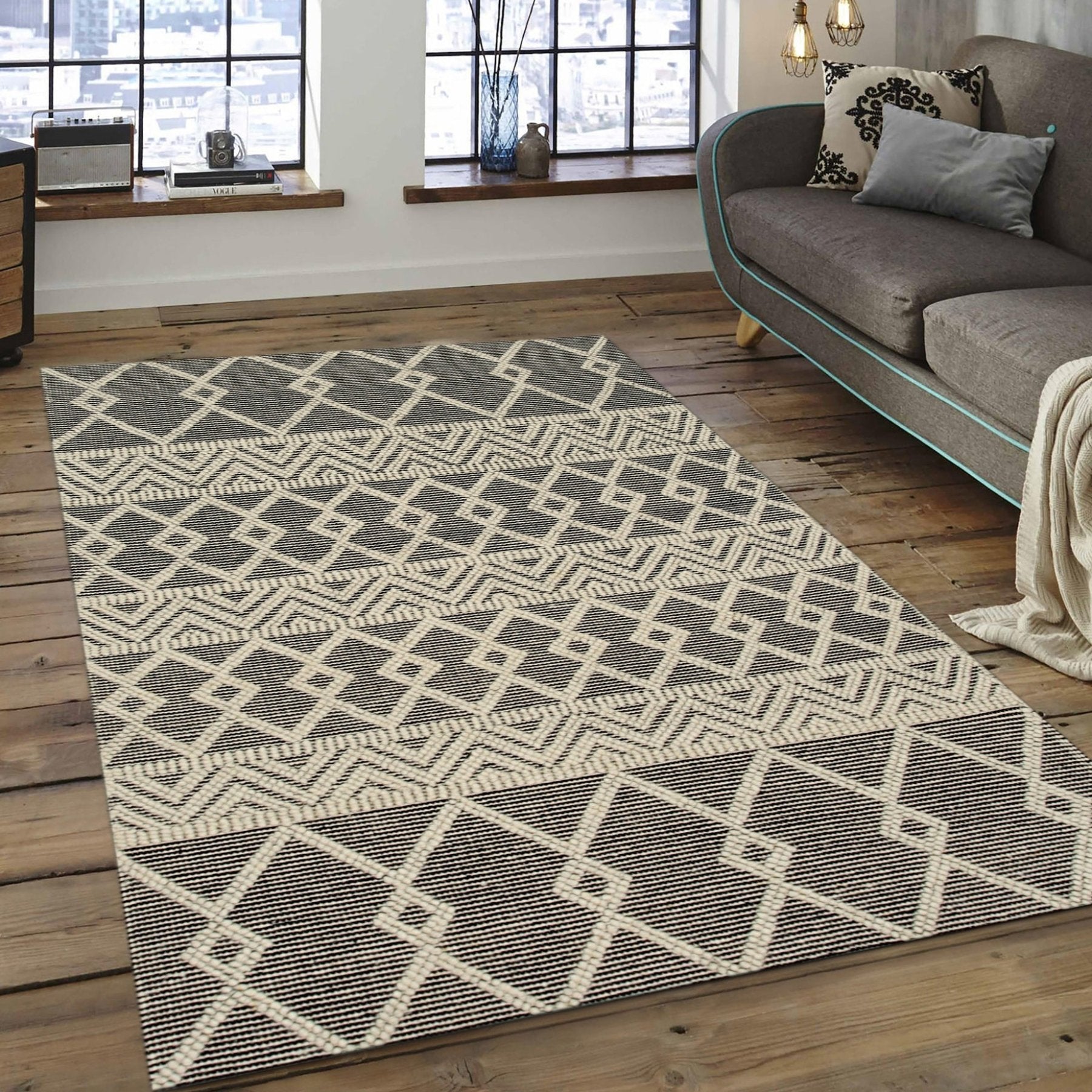 Modern Kilim Black Handmade Wool Rug, its graphic black-and-cream pattern unfolding on a light hardwood floor, showcasing the texture of the hand-woven wool construction in a bright, airy room.