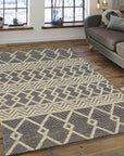 Modern Kilim Black Handmade Wool Rug, its graphic black-and-cream pattern unfolding on a light hardwood floor, showcasing the texture of the hand-woven wool construction in a bright, airy room.
