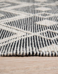 Modern Kilim Black Handmade Wool Rug, showcasing a textured weave with geometric patterns in contrasting black and off-white, lies elegantly on a light hardwood floor, its minimalist design adding sophistication to a modern living space.