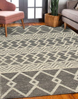 Modern Kilim Black Handmade Wool Rug displayed in a bright living room, its geometric pattern grounding a space with white walls and mid-century modern furniture.