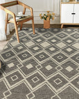 Luna Kilim Black Handmade Wool Rug sprawls across a light wooden floor, its geometric kilim pattern in contrasting tones anchoring a minimalist living space.