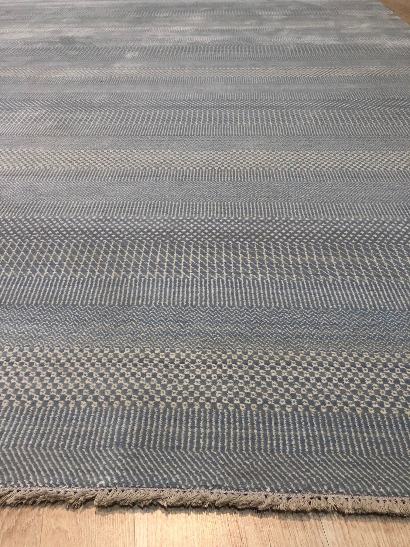 Graceful Comfortable Blue Hand Knotted Wool & Viscose Rug, featuring a soft, blurred pattern of blues and creams, displayed in a bright, modern living room setting.