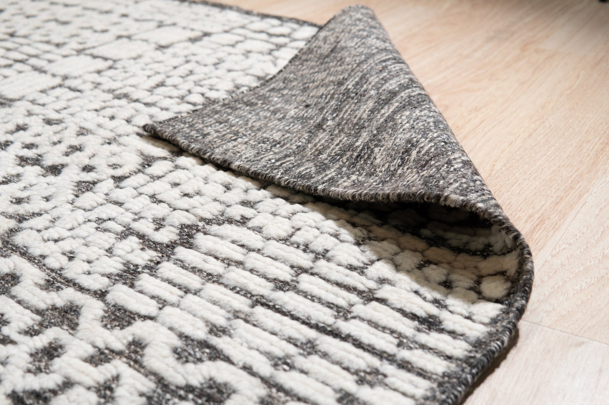 Sloane Sophisticated Ivory Hand Knotted Wool Rug displayed in a bright, airy living room. The ivory wool rug grounds the space with its subtle texture and hand-knotted construction, complementing the neutral tones and natural light.