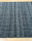 Delicate Elena Blue Flatweave Wool Rug, a soft blue wool rug with a subtle geometric pattern, lies flat on a light wood floor, subtly textured and inviting.