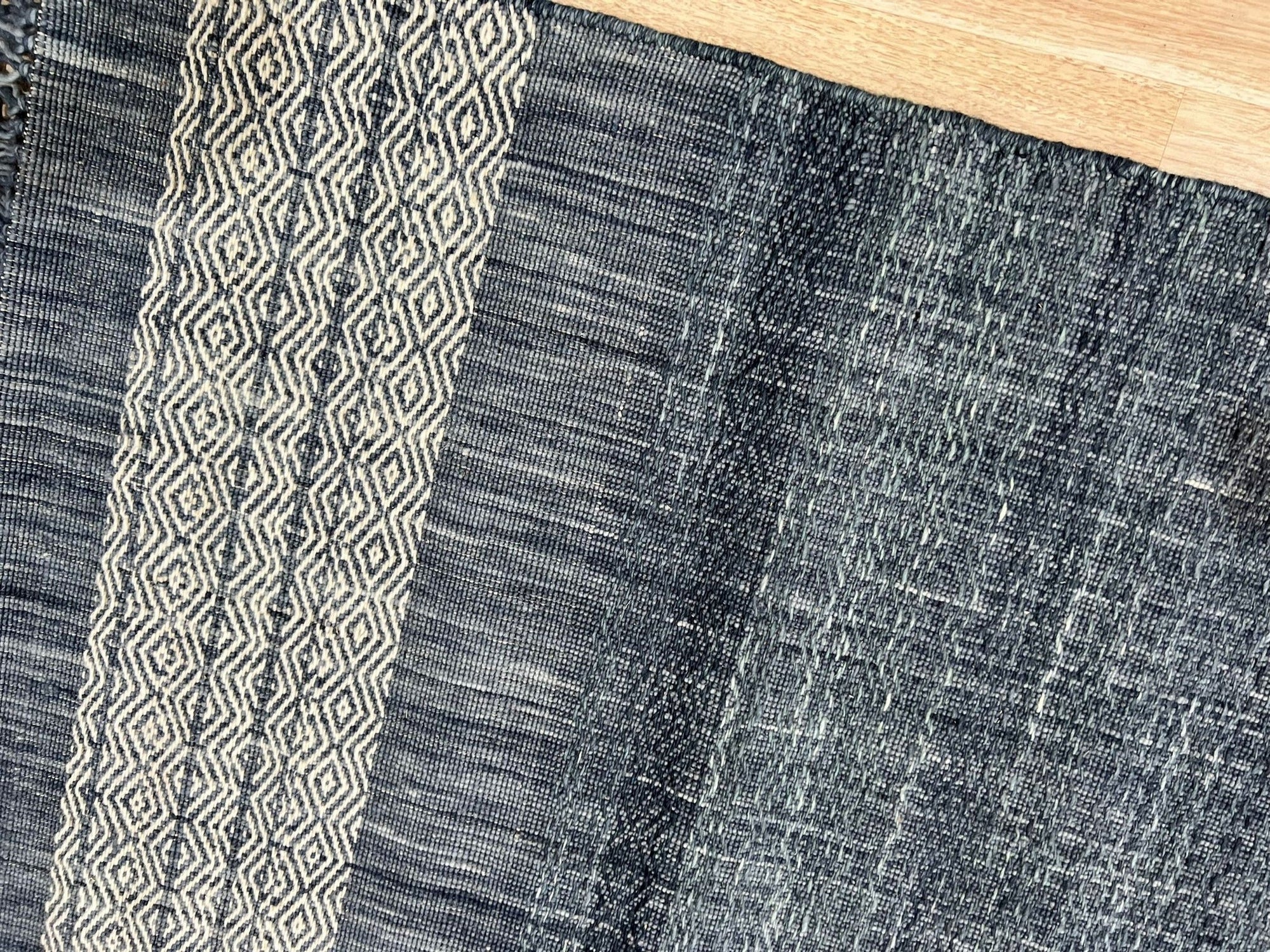 Delicate Elena Blue Flatweave Wool Rug, showcasing its textured flatweave construction and serene blue hues, layered in a modern living room setting with light wood furniture and natural light.