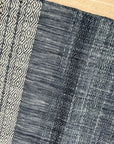 Delicate Elena Blue Flatweave Wool Rug, showcasing its textured flatweave construction and serene blue hues, layered in a modern living room setting with light wood furniture and natural light.