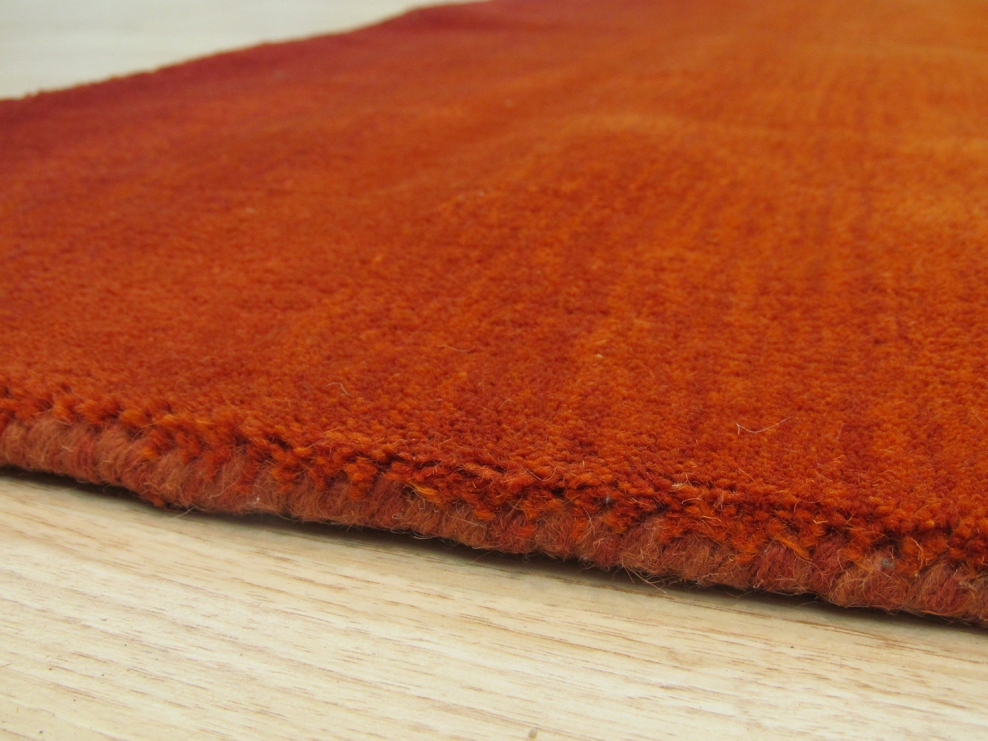 Ruby Classic Orange Handmade Wool Rug displayed: close-up reveals intricate geometric patterns in warm oranges, creams, and touches of brown, hand-knotted in soft, luxurious wool.