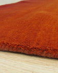 Ruby Classic Orange Handmade Wool Rug displayed: close-up reveals intricate geometric patterns in warm oranges, creams, and touches of brown, hand-knotted in soft, luxurious wool.