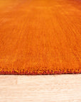 Ruby Classic Orange Handmade Wool Rug, showcasing vibrant orange hues and intricate patterns, laying in a brightly lit living room setting.