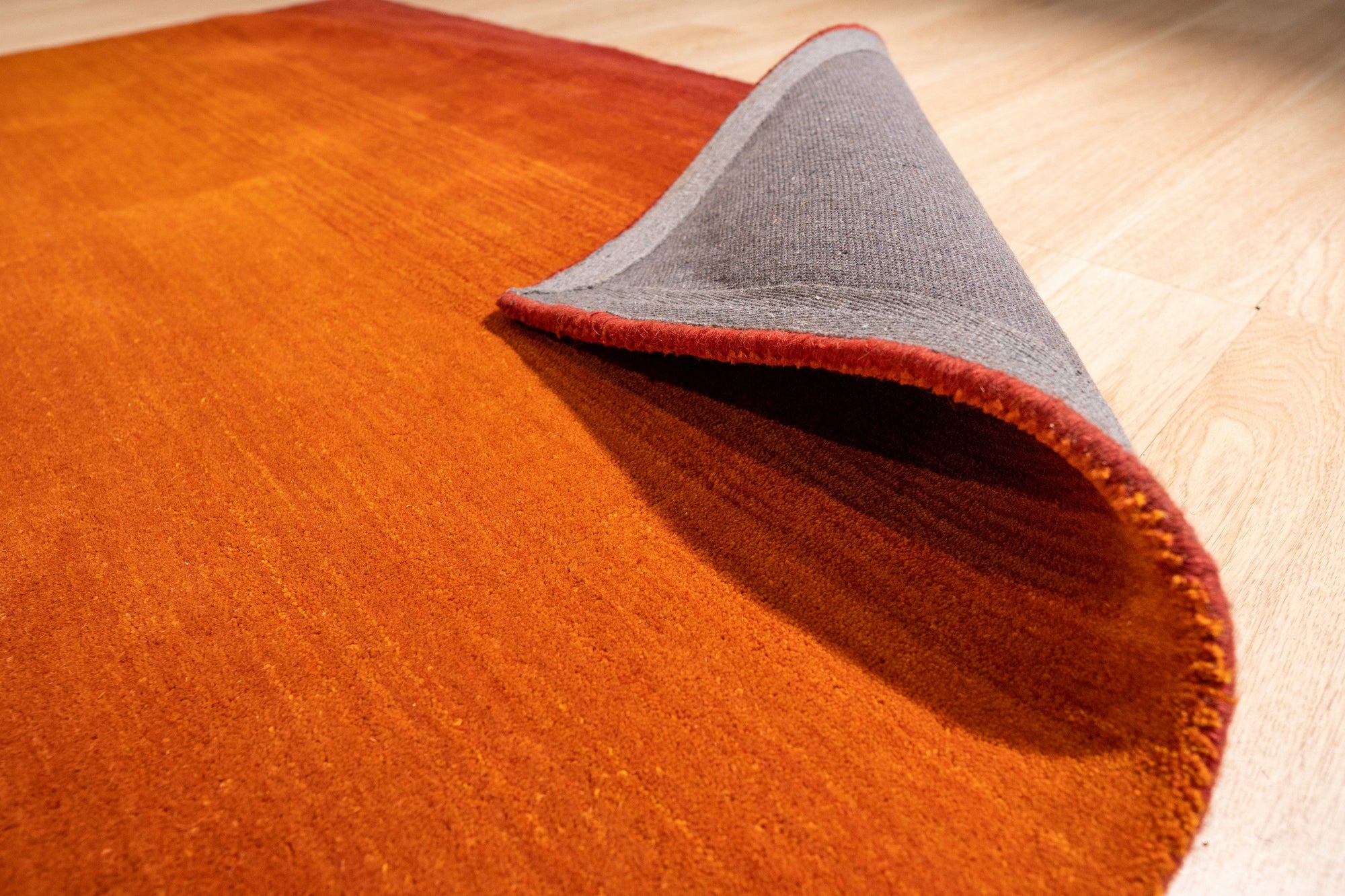 Ruby Classic Orange Handmade Wool Rug, vibrant hues of orange and deep reds intertwine in a traditional floral motif. Dense, hand-knotted wool creates a luxurious texture, showcased within a modern living space.