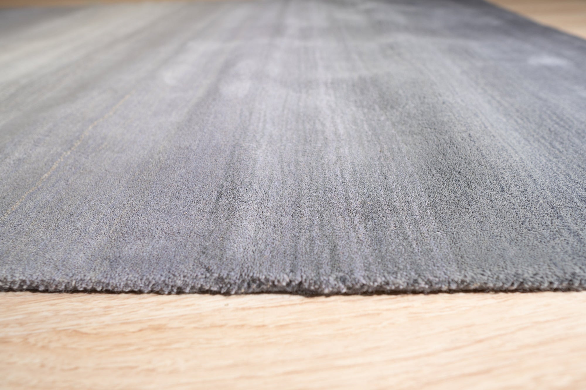 Modern Talia Gray Handmade Wool Rug displayed on a light wood floor, showcasing its subtle geometric pattern and textured weave in muted gray tones.