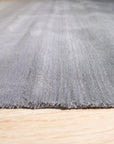 Modern Talia Gray Handmade Wool Rug displayed on a light wood floor, showcasing its subtle geometric pattern and textured weave in muted gray tones.