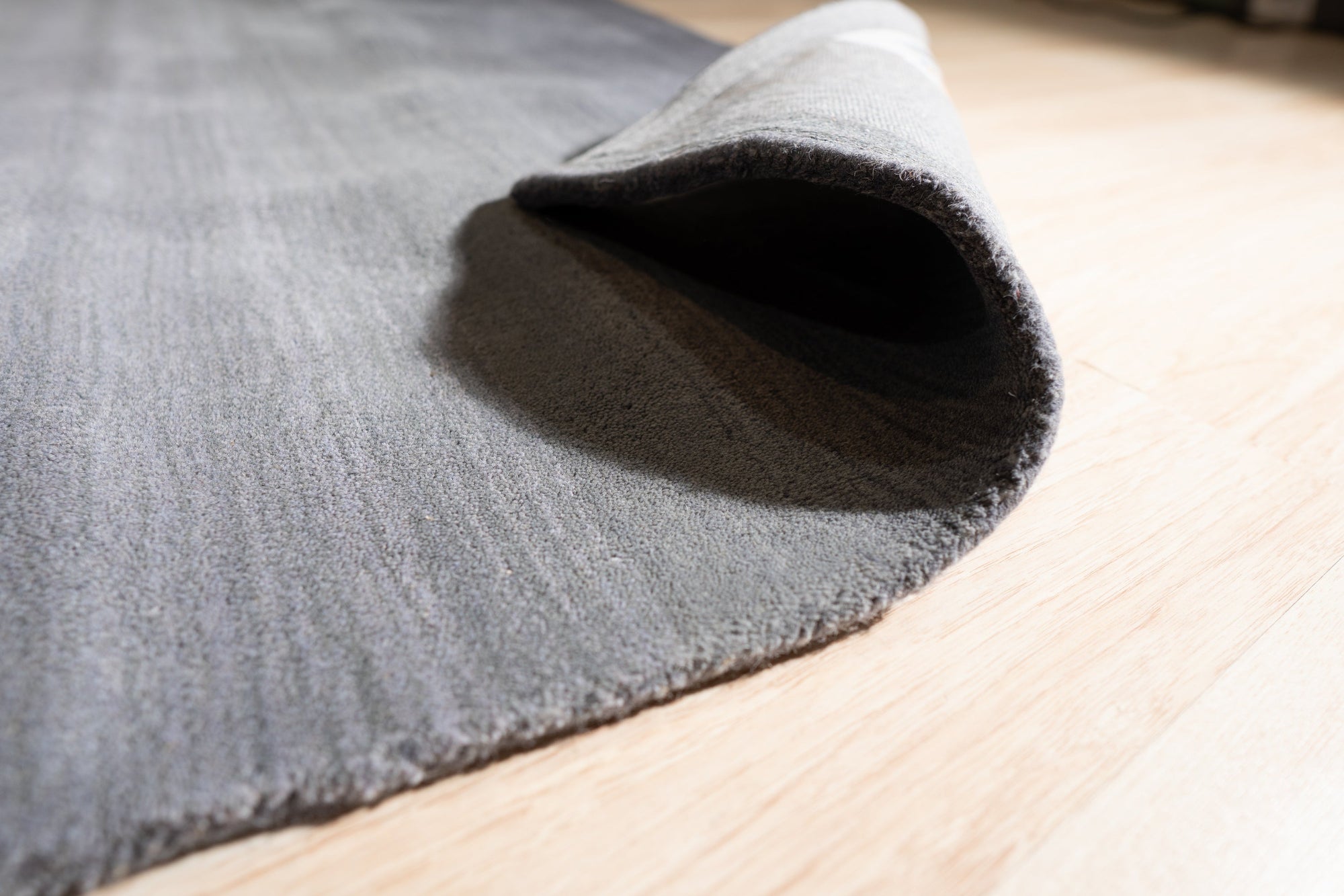 Modern Talia Gray Handmade Wool Rug, showcasing subtle geometric patterns in varying shades of gray, its handwoven texture adding depth and warmth to a living room setting.