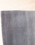 Modern Talia Gray Handmade Wool Rug, showcasing subtle geometric patterns in varying shades of gray, lies on a light hardwood floor in a bright living space; neutral furniture complements the rug's calming color palette.