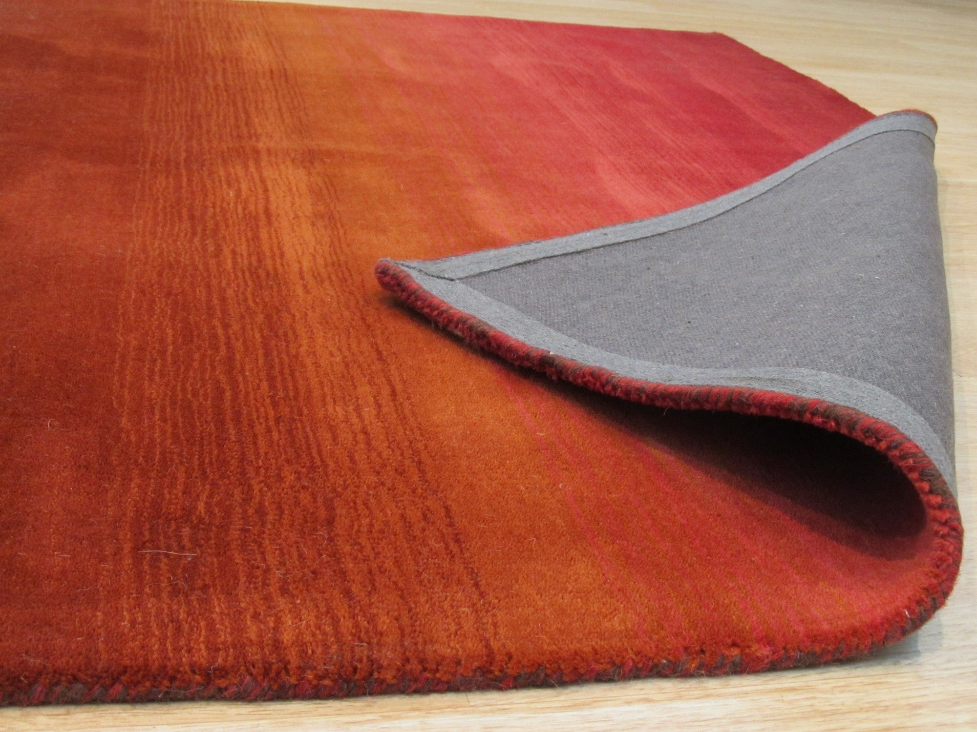 Rhea Unique Multicolor Handmade Wool Rug, displaying vibrant hues of blue, orange, yellow, and red in a captivating geometric pattern. Hand-knotted wool construction provides texture and warmth in a modern living space.